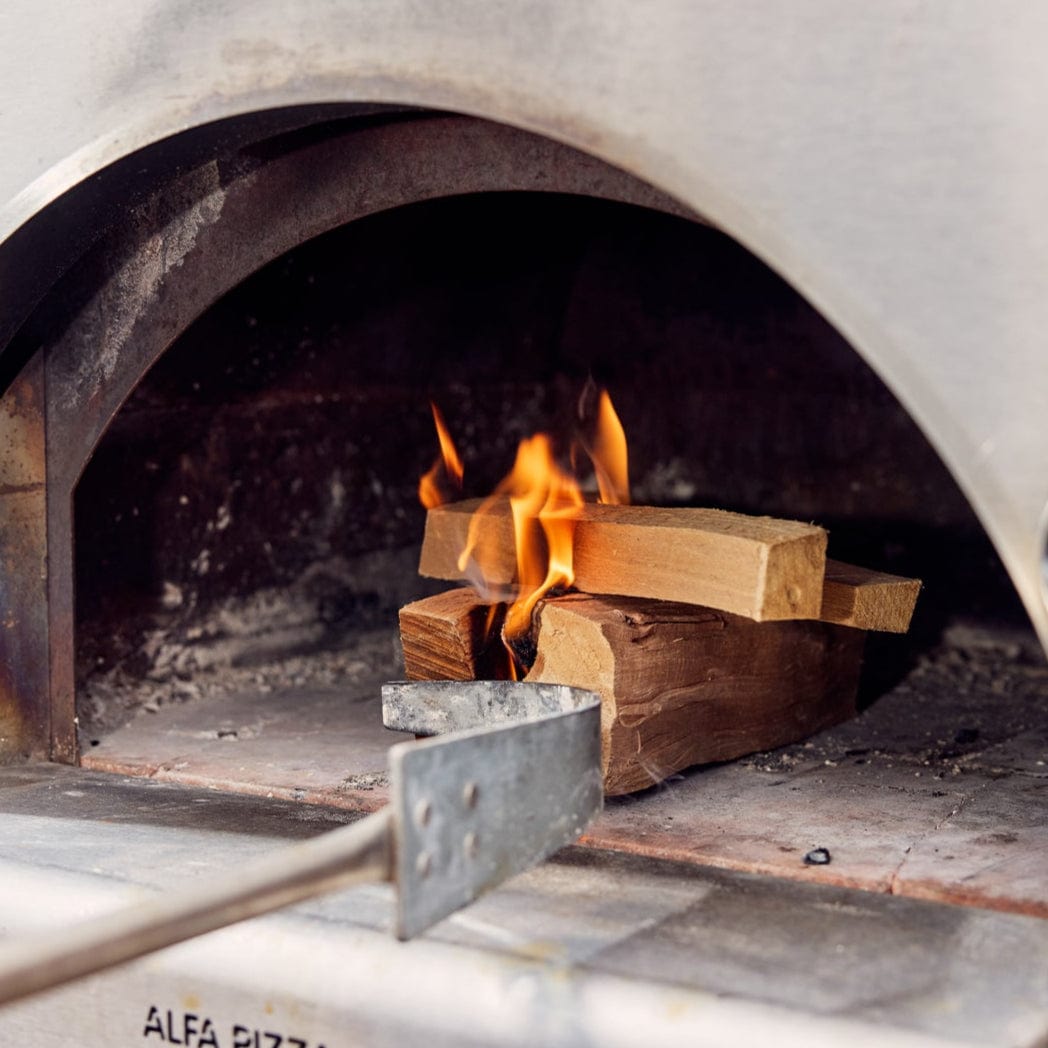 Wood-fired pizza oven with flames and wood logs inside