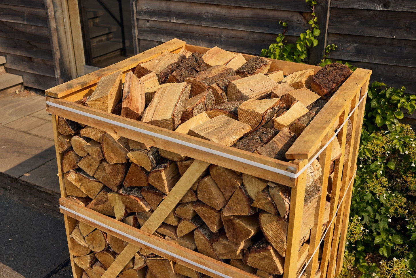 Stack of firewood in a wooden crate against a wooden wall.