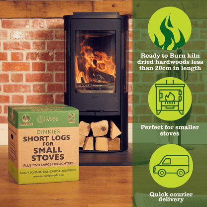 Wood-burning stove with a box of short logs and firelighters against a brick wall.