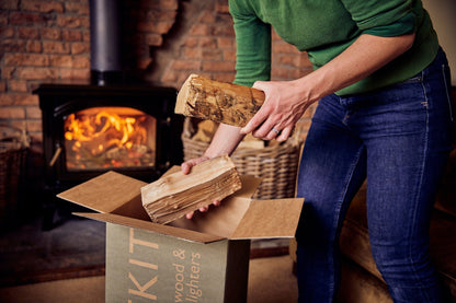 Person unloading  firewood from a box in front of a woodburner