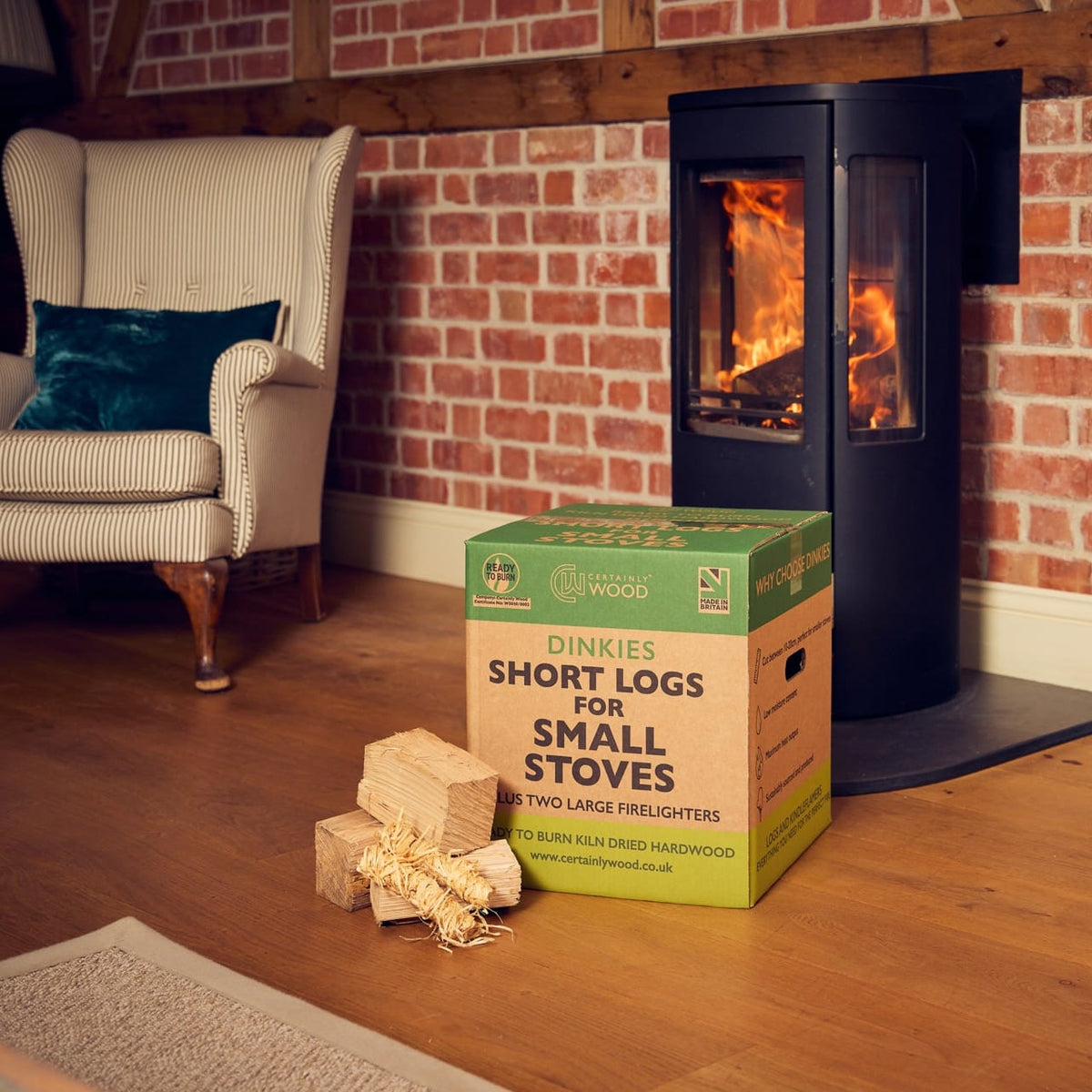Wood-burning stove with a box of Dinkies logs in a cozy living room.