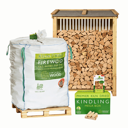 A wood storage and firewood bundle featuring a large bulk bag of Certainty Wood kiln dried firewood on a wooden pallet, a tall wooden log store filled with logs, and a green box of Premier Kiln Dried Kindling Mega Kindling with a Flamers natural firelighters pack
